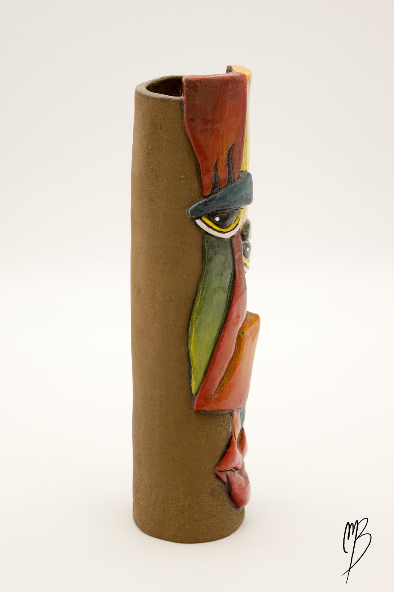 vase haut et fin orné d'un visage abstrait rouge jaune vert et bleu en terre émaillé, vu de profil gauche