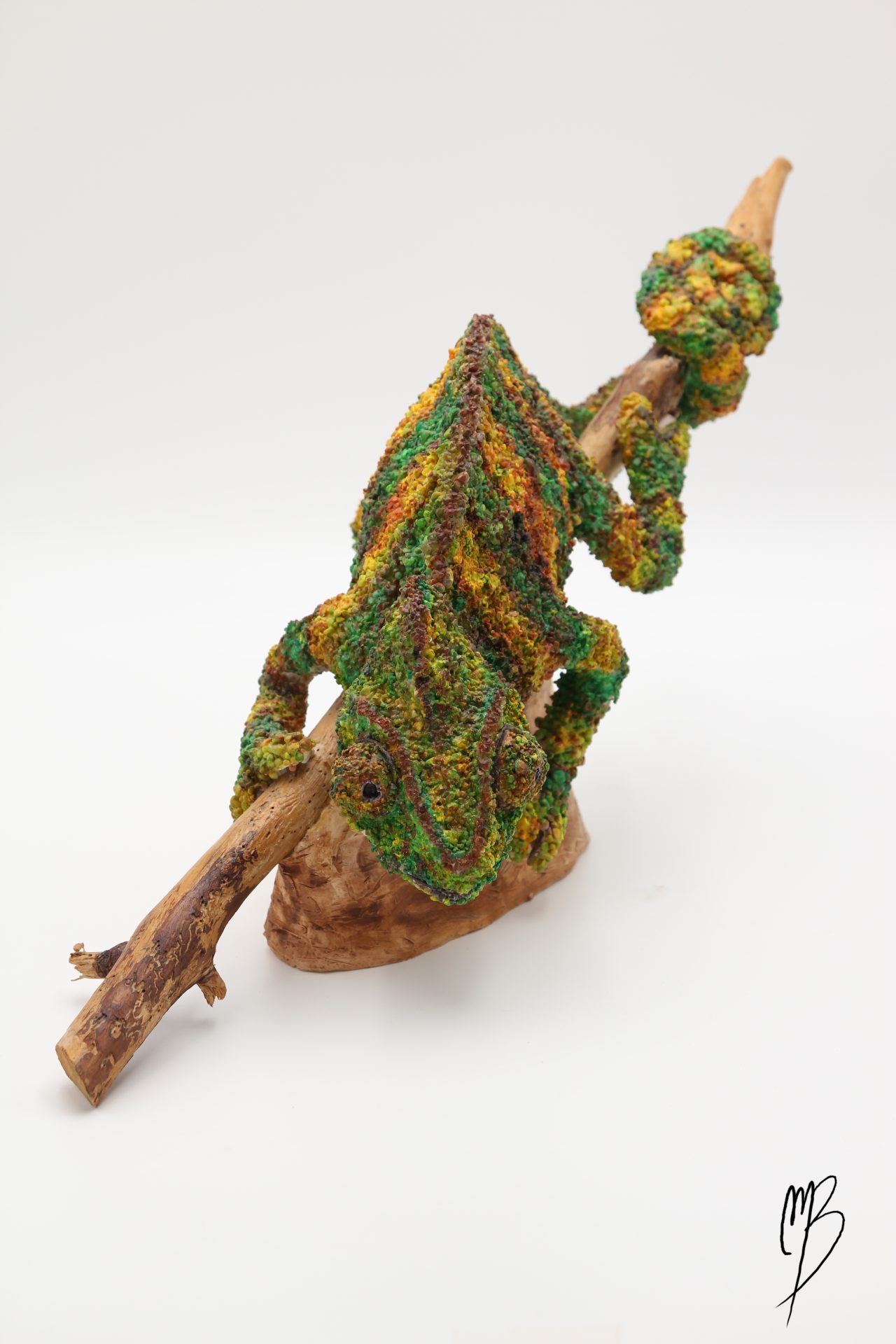 Sculptures. Animaux. Caméléon sur sa branche en terre cuite recouvert de sable et de peinture acrylique vernie. Vue de dos