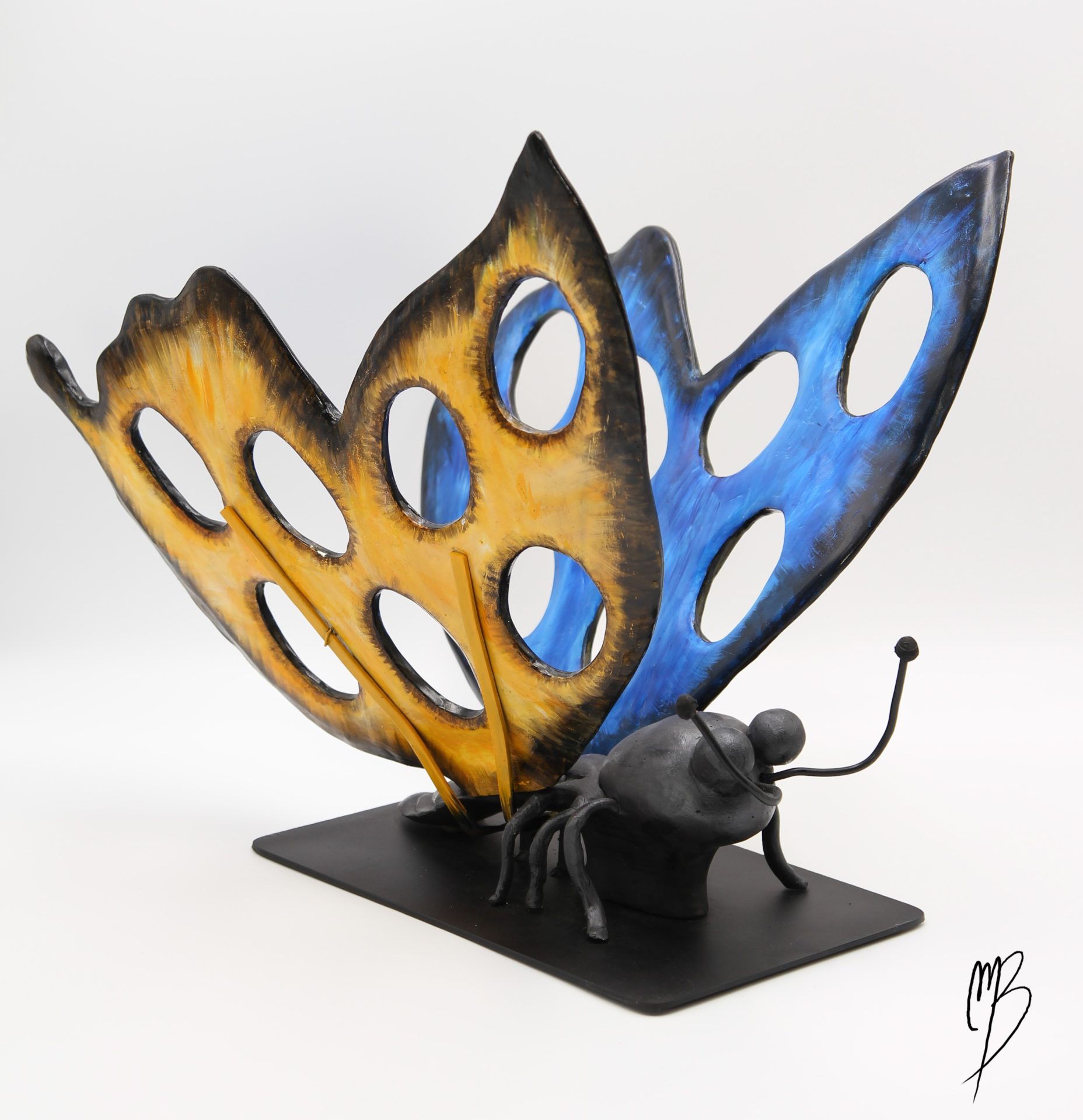 Sculptures. Animaux. Morpho Bleu aux ailes déployées jaunes et bleues sur un socle en métal en terre cuite recouverts de peinture acrylique vernie.