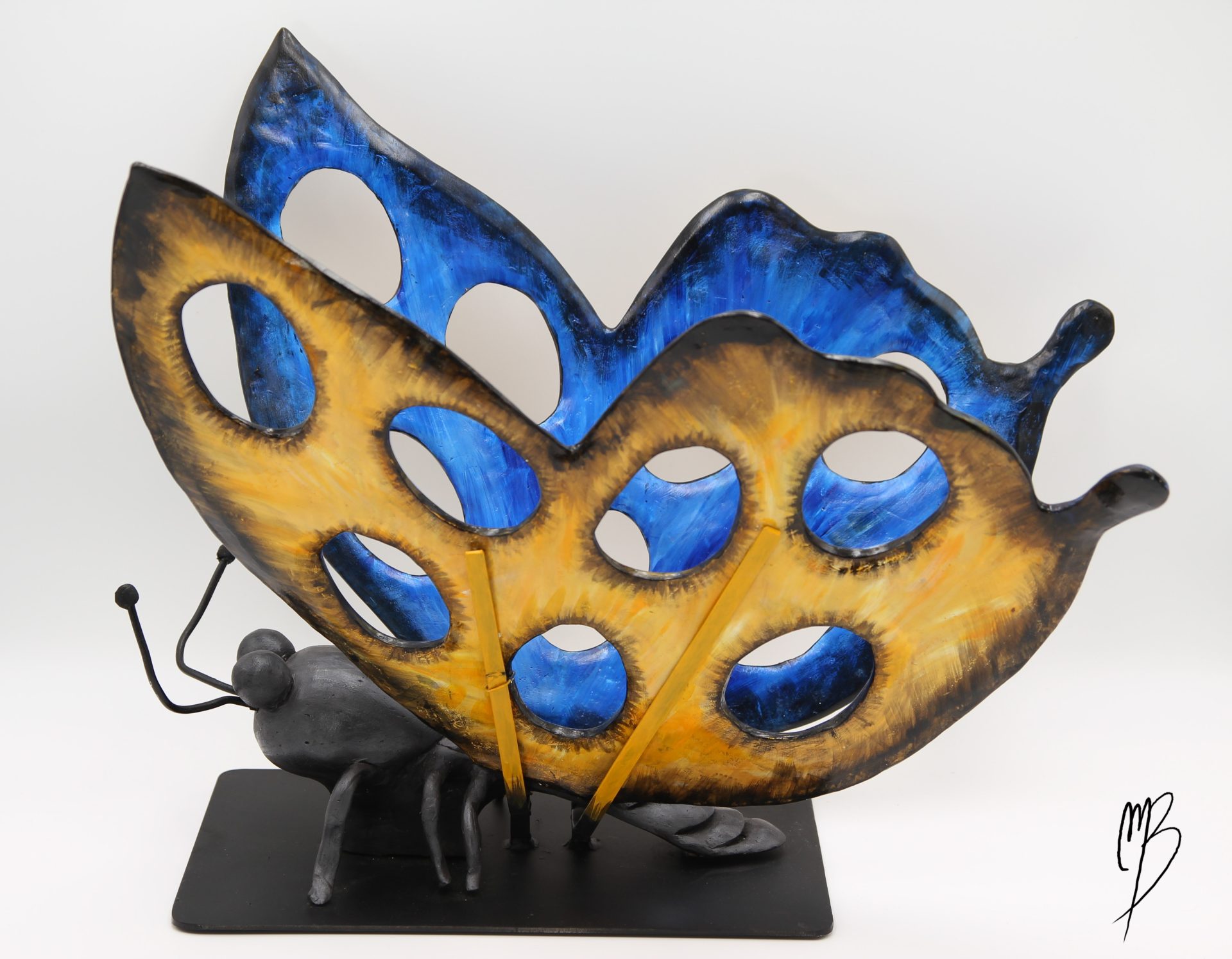 Animaux. Morpho Bleu aux ailes déployées jaunes et bleues sur un socle en métal en terre cuite recouverts de peinture acrylique vernie. Vue de côté