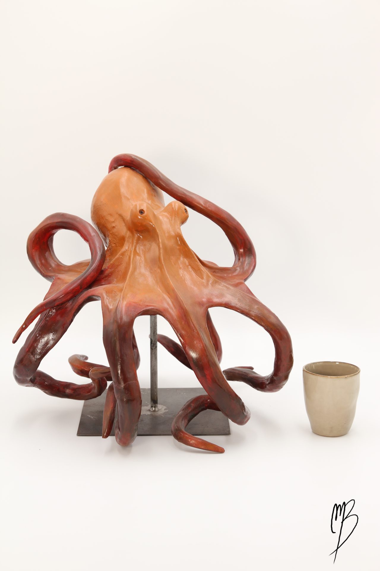 Animaux. Pieuvre sur un socle en métal en terre cuite recouverts de peinture acrylique vernie. Vue comparative à une tasse pour la taille