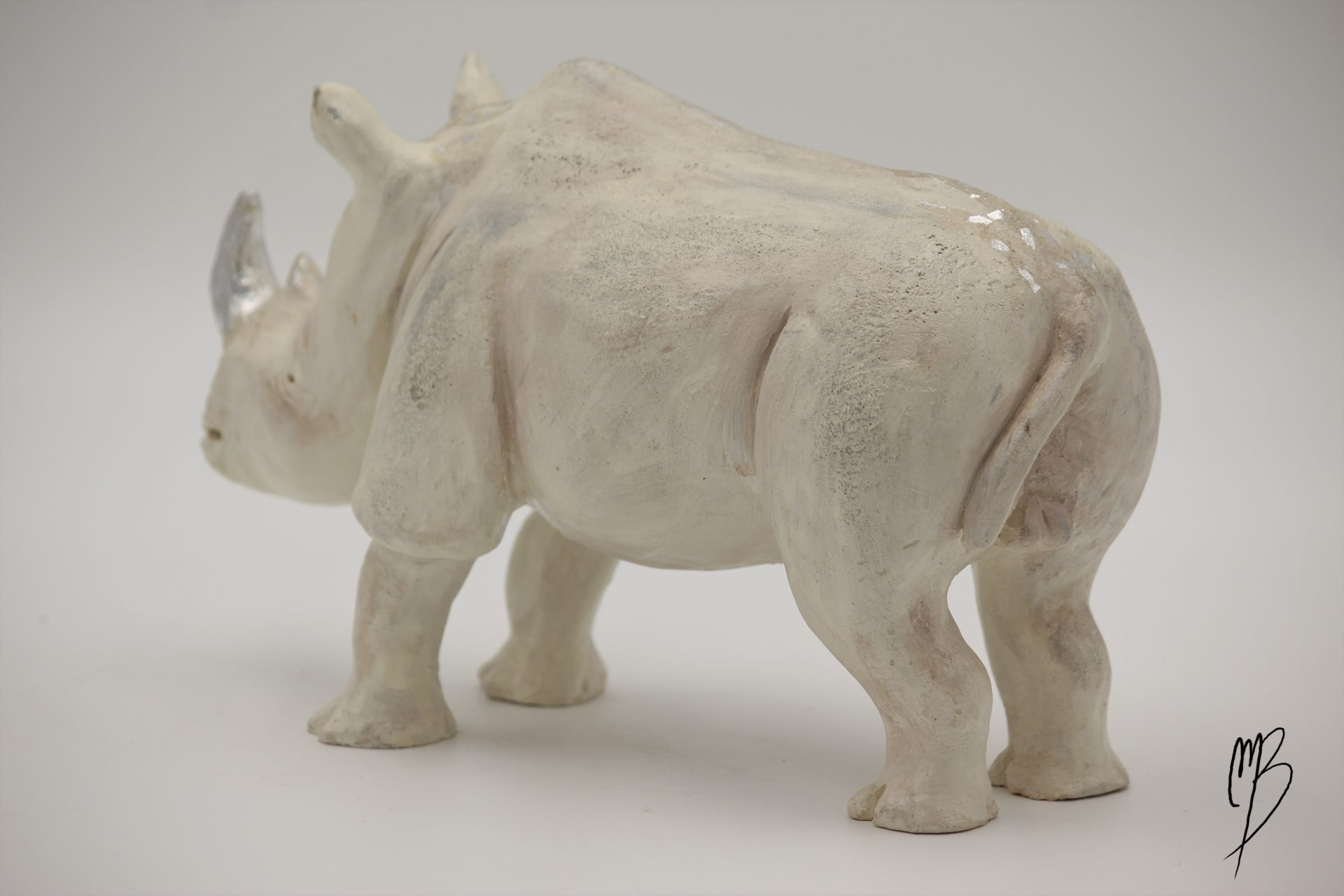 Animaux. Rhinocéros en terre cuite recouvert de peinture acrylique et de feuilles d'argent. Vue de trois quart arrière