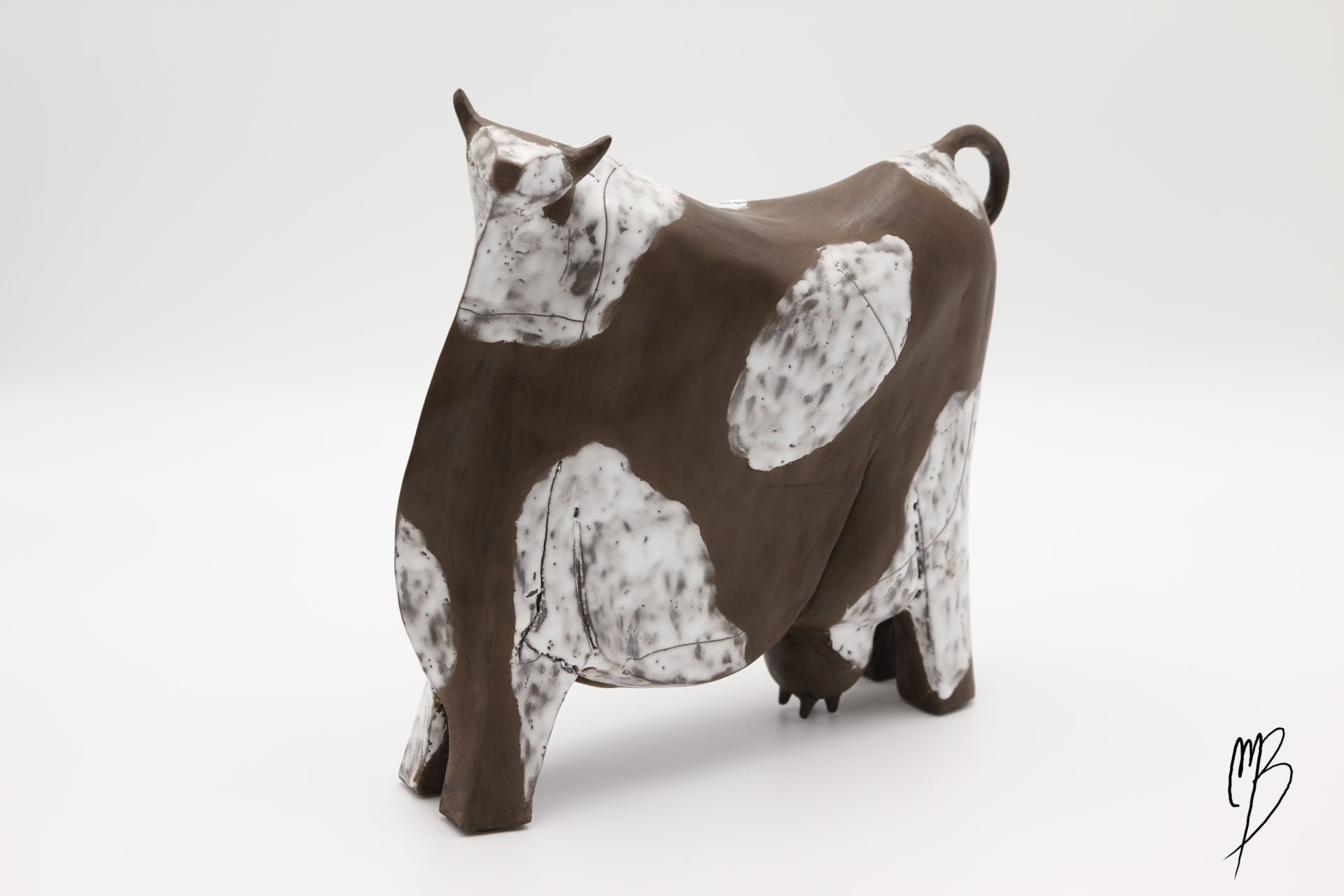 Animaux. Vache stylisée marron en terre cuite avec des tâches blanches émaillées. Vue de face et côté.