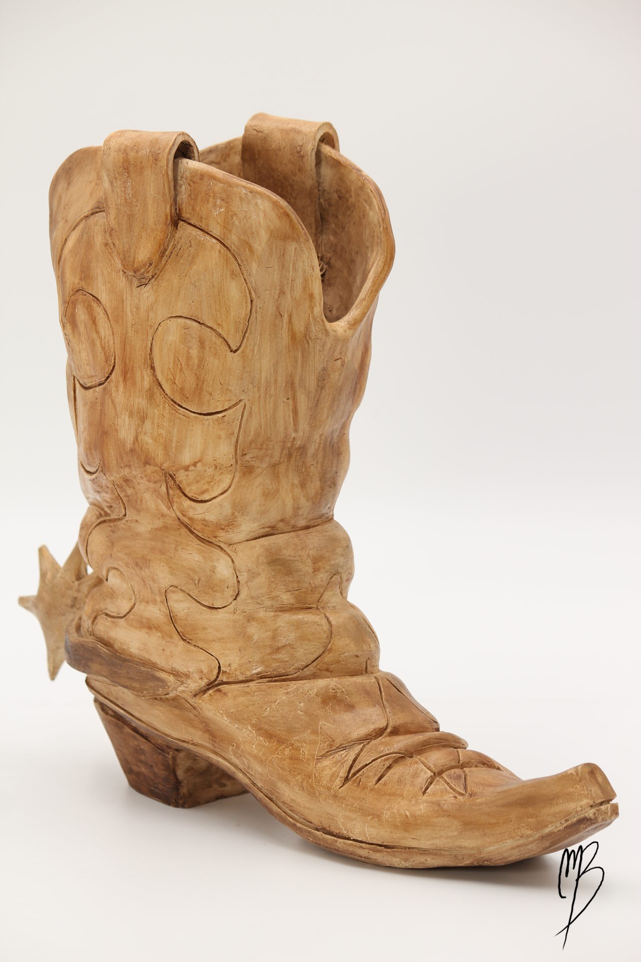 Sculptures contemporaine en Terre cuite patinée avec une peinture acrylique ocre terre du désert. Elle représente une botte de cowboy Santiag avec son éperon.