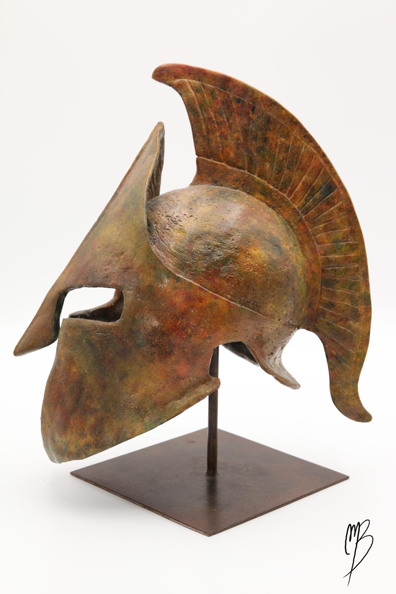 Casque Spartiate posé sur un support métallique en Terre cuite patinée avec des peintures acryliques imitant des bronzes anciens. Vue de côté.