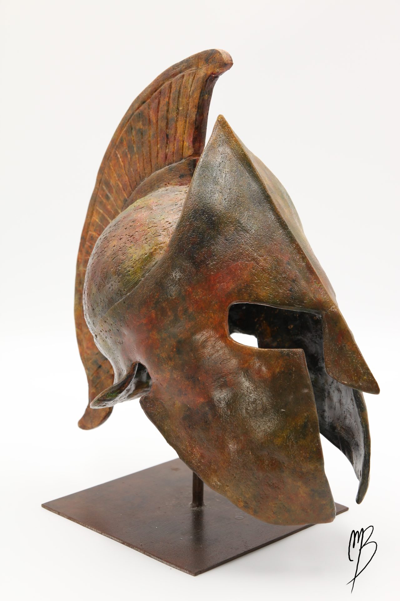 Sculptures en Terre cuite patinée avec des peintures acryliques imitant des bronzes anciens. Elle représente un casque Spartiate posé sur un support métallique.