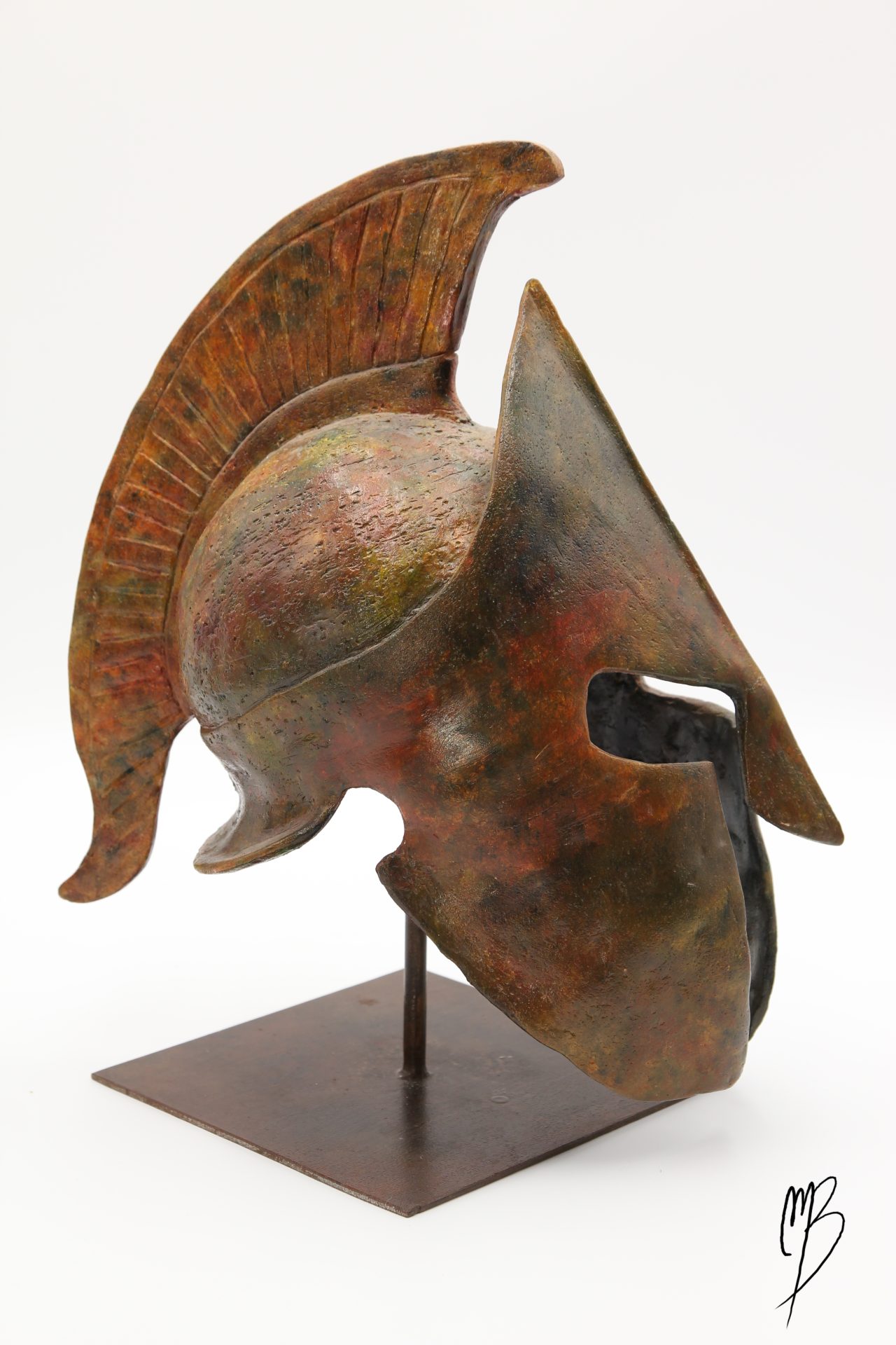 Casque Spartiate posé sur un support métallique en Terre cuite patinée avec des peintures acryliques imitant des bronzes anciens. Vue de côté.