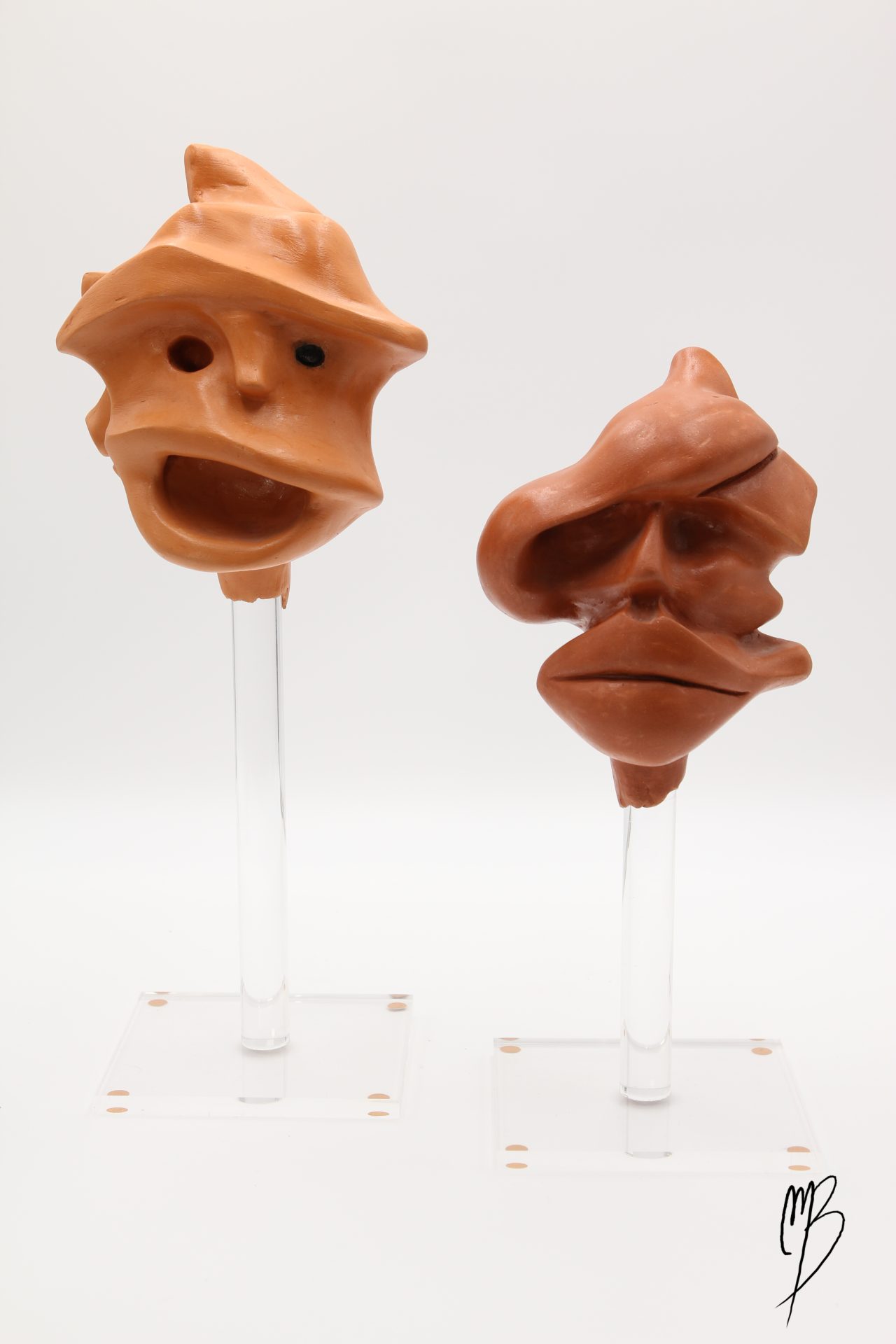 Sculptures. Deux prises d'escalade représentant deux têtes de primate en terre cuite vernie reposant sur deux socle transparent en plexiglass. Vue de face