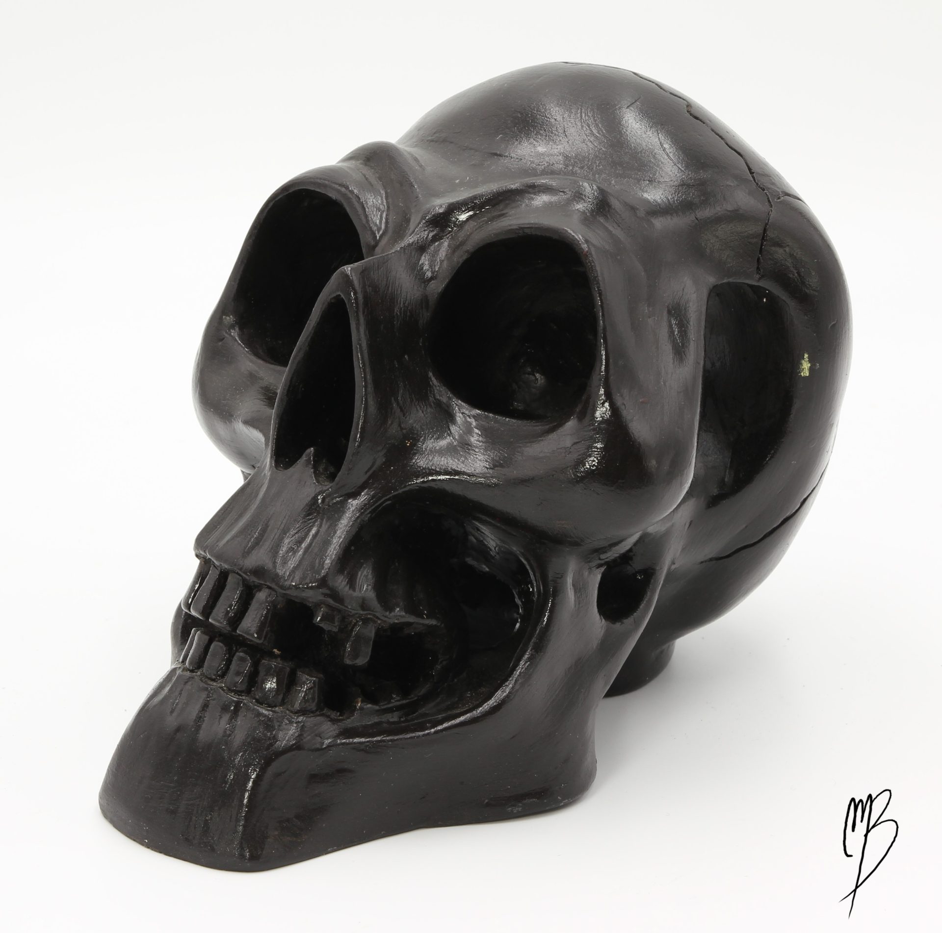Tête de mort en terre cuite recouverte de peinture acrylique noire et vernie. Vue de trois quart.