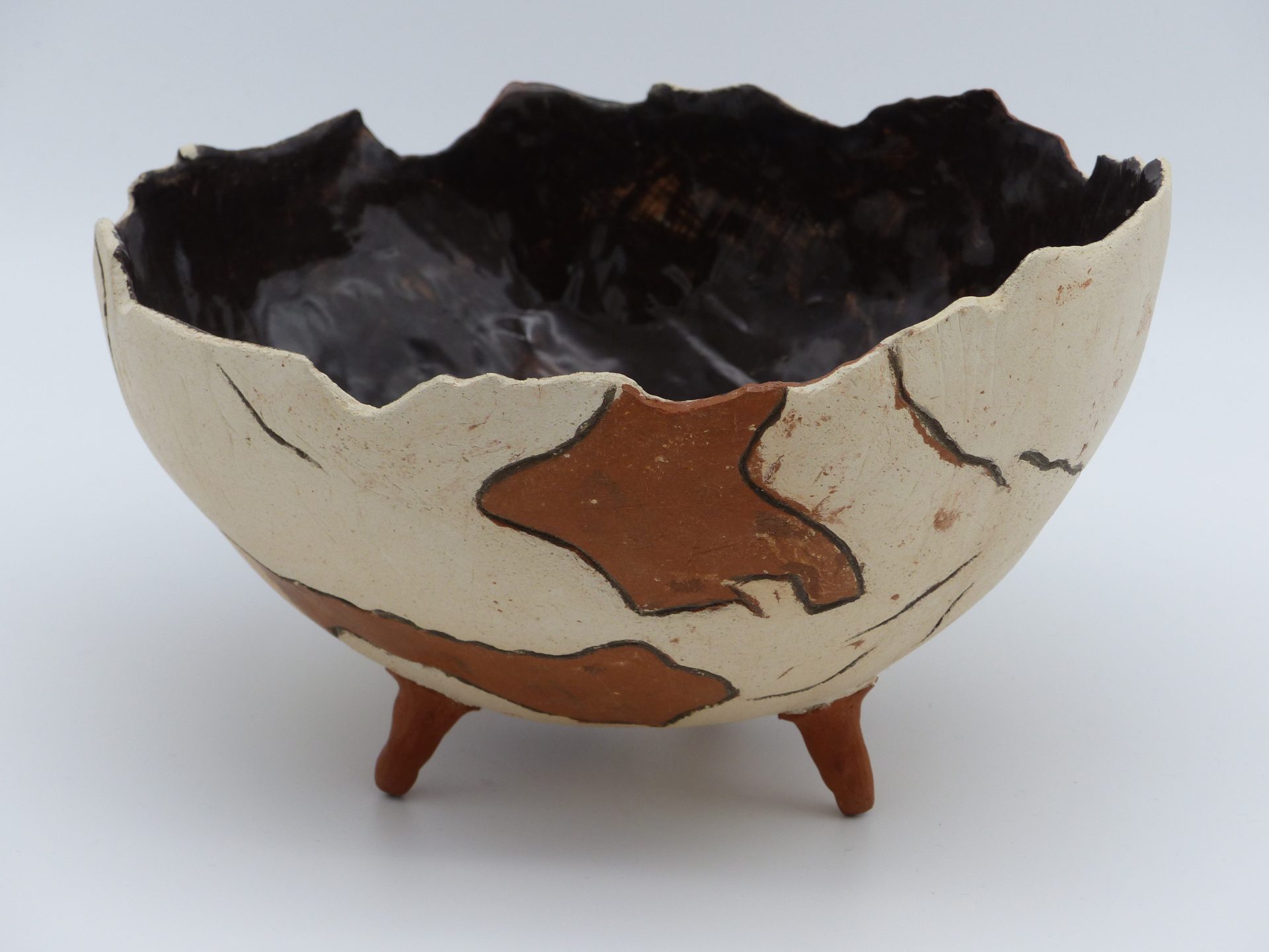 demie coupe façon poterie antique brisée, posée sur trois petits pieds, en terre cuite, avec l'intérieur émaillé noir, et l'extérieur bicolore marron et beige ciré, vue de face