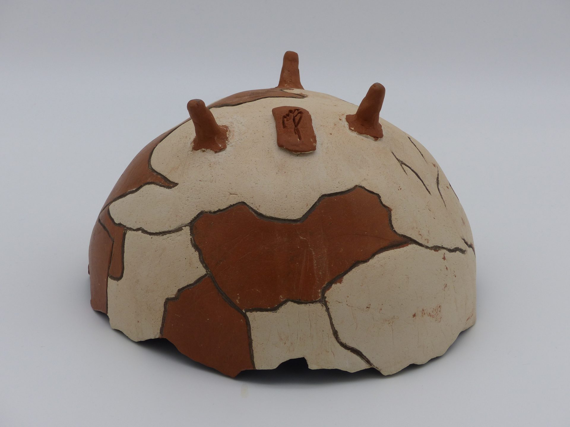 demie coupe façon poterie antique brisée, posée sur trois petits pieds, en terre cuite, avec l'intérieur émaillé noir, et l'extérieur bicolore marron et beige ciré, vue à l'envers