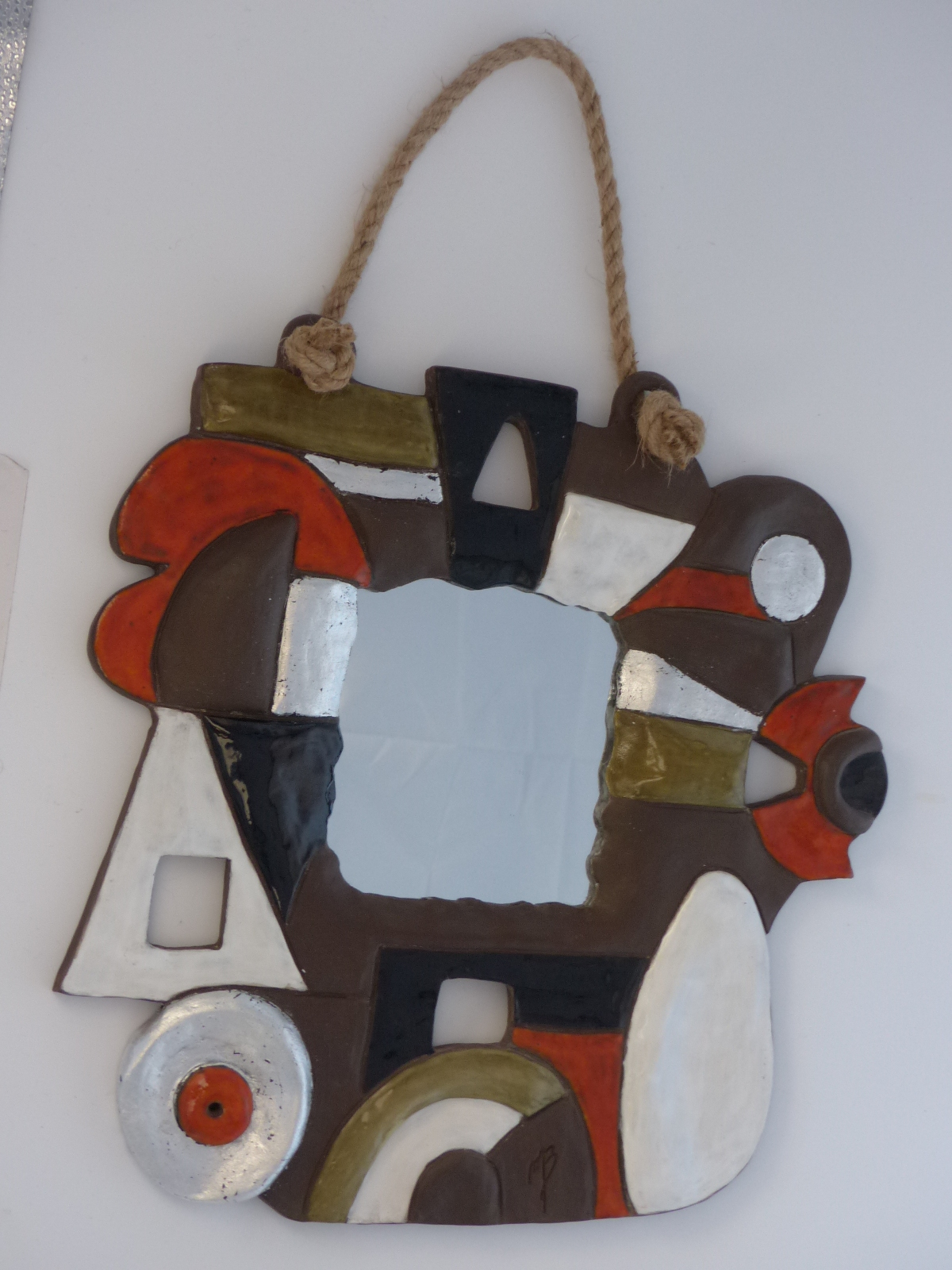 modelages sculptures d'un miroir multicolore en terre cuite aux décors émaillées et recouverts en partie de feuilles d'argent, avec sa corde d'accrochage